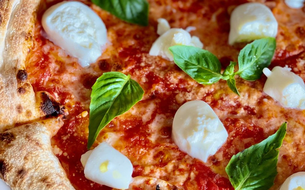 Margherita pizza topped with melted Roomeys Pizzarella cheese and fresh basil